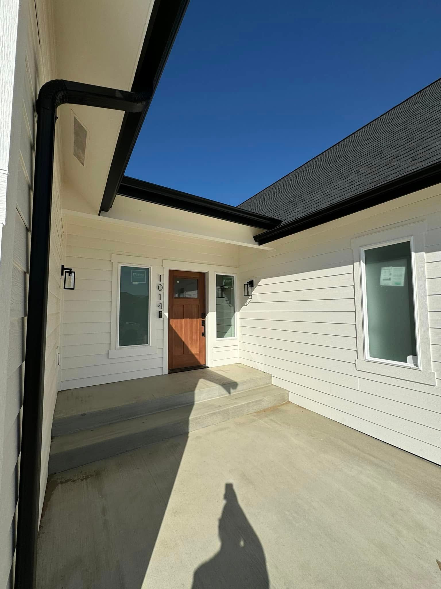 A white house with a wooden door and a black gutter