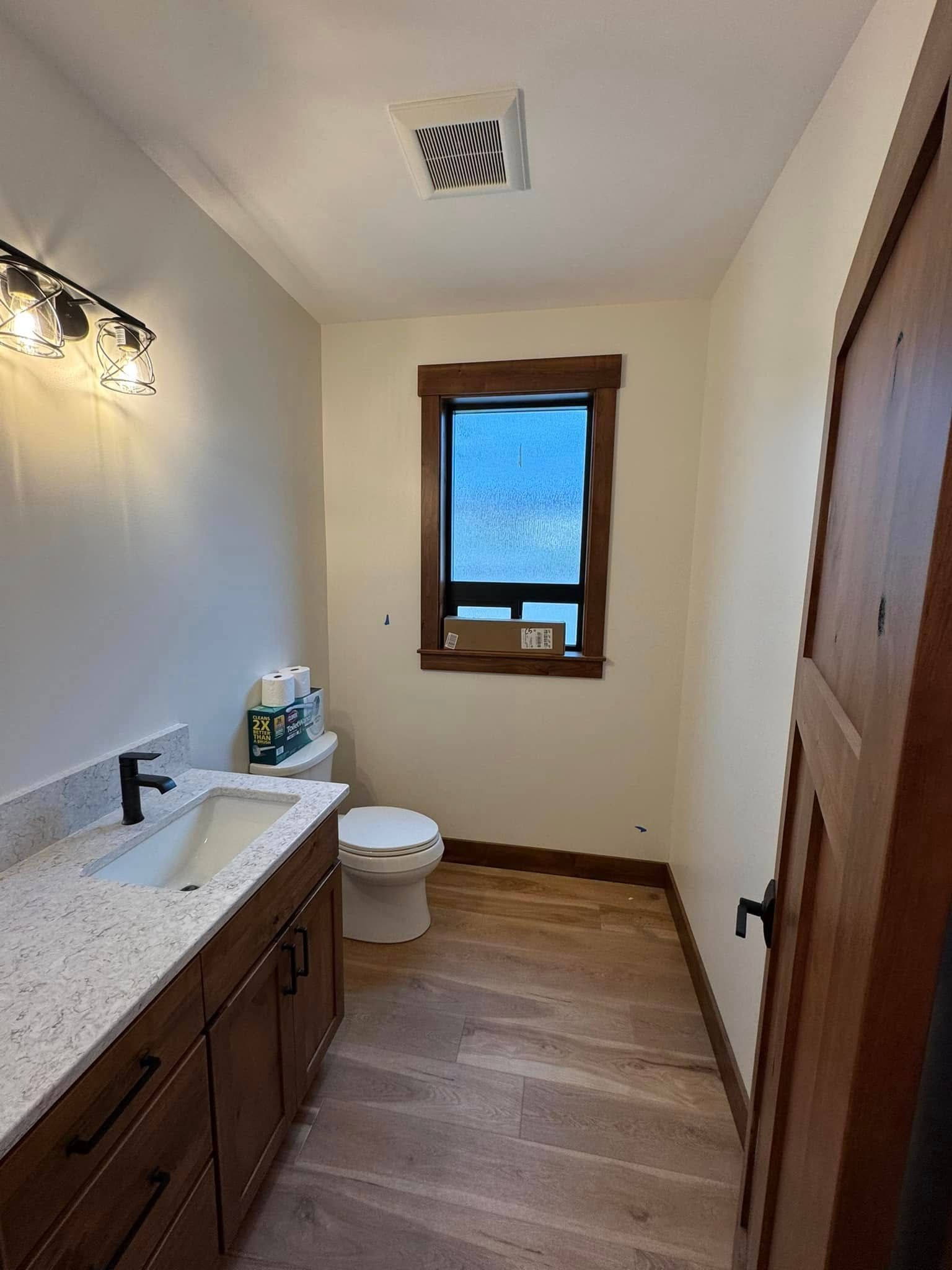 A bathroom with a sink , toilet , and window.