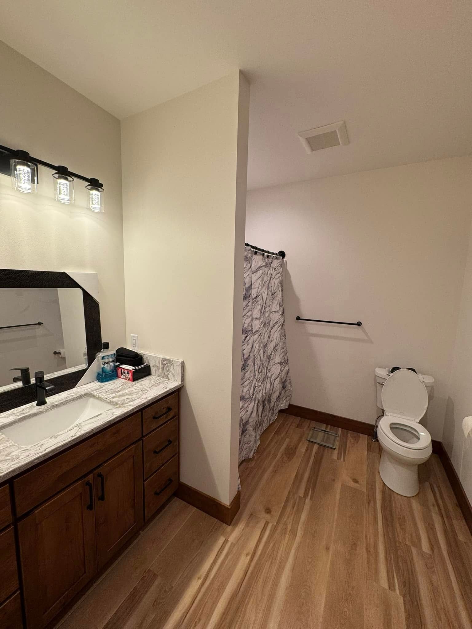 A bathroom with a toilet , sink and mirror.