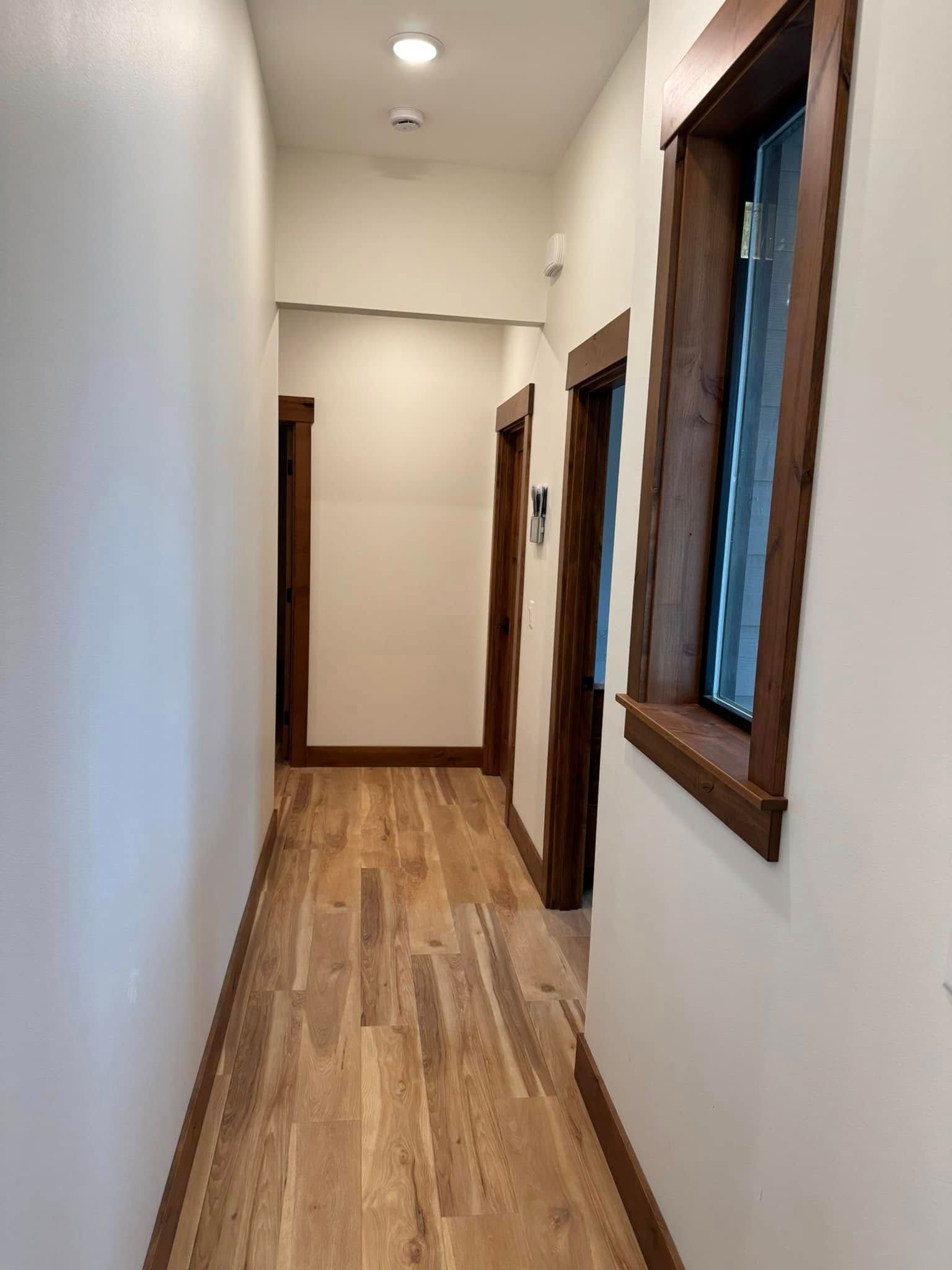A long hallway with wooden floors and white walls.