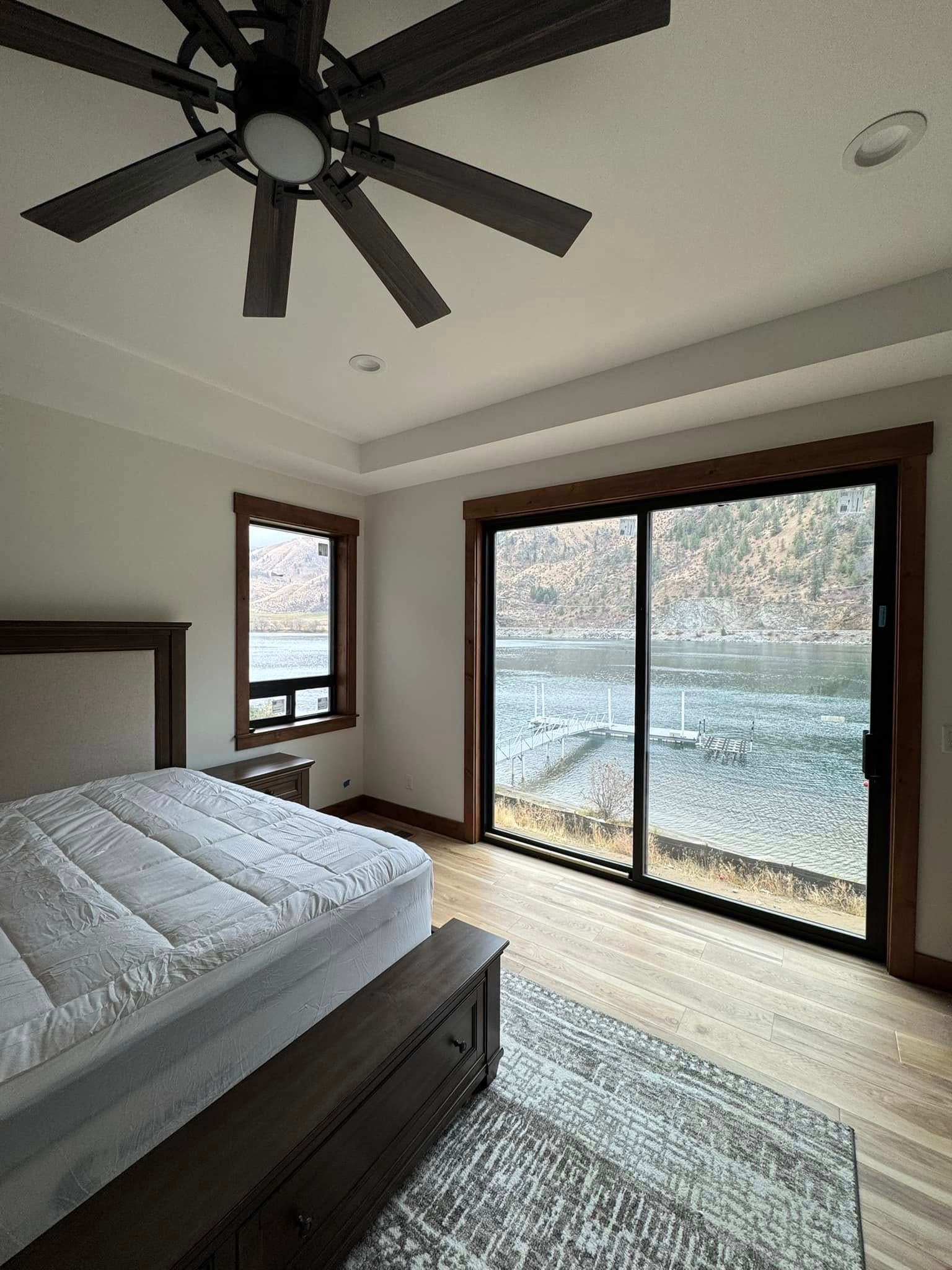 A bedroom with a bed , ceiling fan , and sliding glass doors.