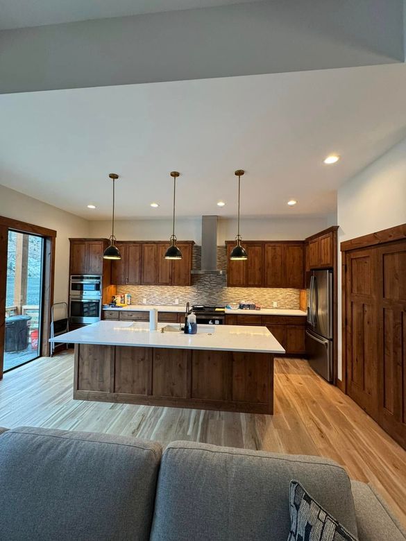 A kitchen with wooden cabinets and a large island in the middle of the room.