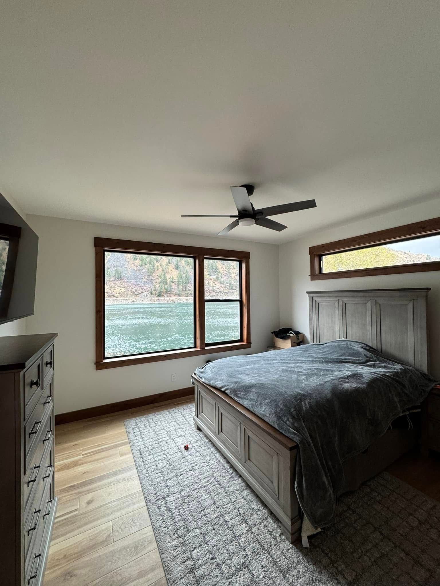 A bedroom with a bed , dresser , and ceiling fan.