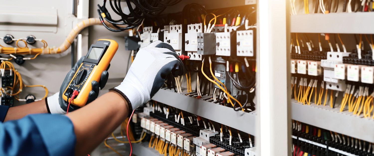 Technician using multimeter for electrical repair services on commercial breaker panel system. Technician using multimeter for electrical repair services on commercial breaker panel system.