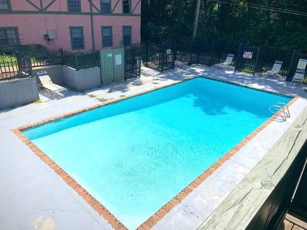 Swimming pool with blue water surrounded by a brick border and gray concrete.