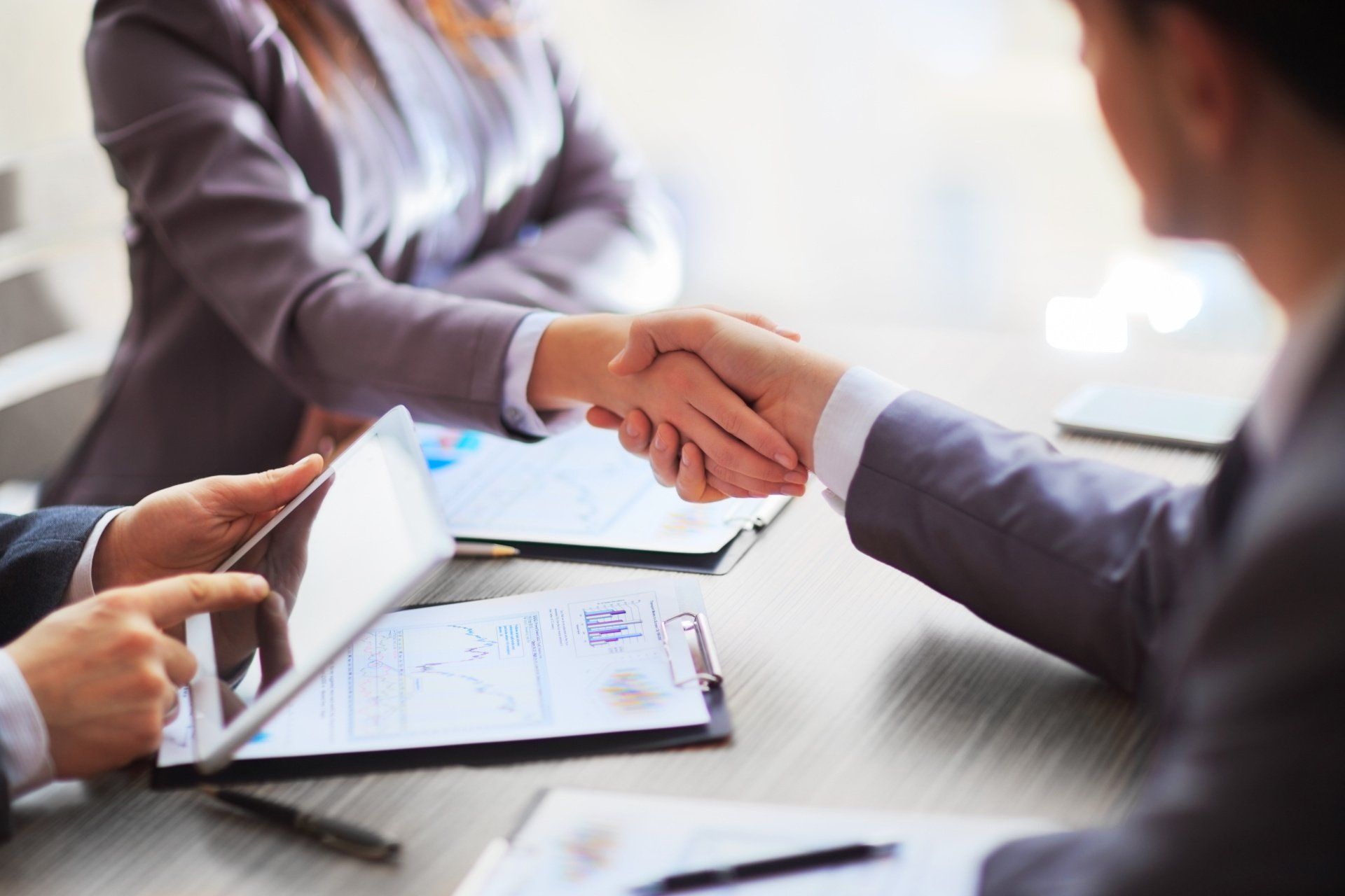 A man and a woman are shaking hands over a table.