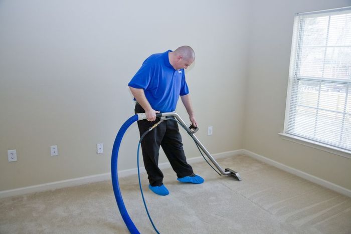a man using a vacuum to clean a carpet