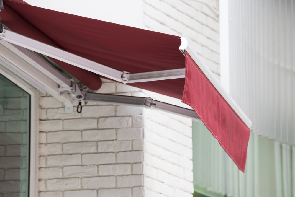 A Red Awning is Hanging From the Side of a Building — Budget Screens & Awnings in Evans Head, NSW