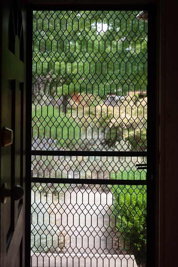 A Door With a Chain Link Fence and a View of a Garden — Budget Screens & Awnings in Ocean Shores, NSW