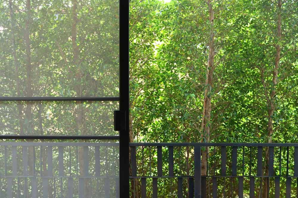 A Sliding Glass Door With Trees in the Background — Budget Screens & Awnings in Lismore, NSW