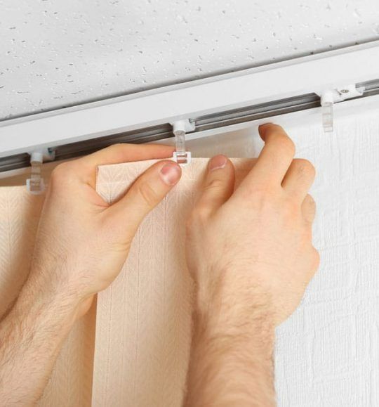 A Person is Installing Vertical Blinds on a Wall — Budget Screens & Awnings in South Lismore, NSW