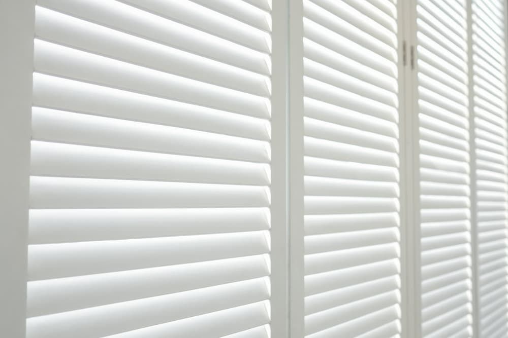 A Close Up of a Row of White Shutters on a Window — Budget Screens & Awnings in South Lismore, NSW