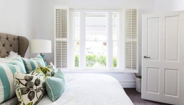 A Bedroom With a Bed, Pillows, Lamps and a Window — Budget Screens & Awnings in Lismore, NSW