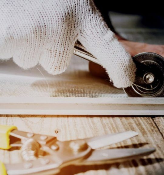 A Person Wearing a White Glove is Holding a Tool on a Wooden Table — Budget Screens & Awnings in South Lismore, NSW