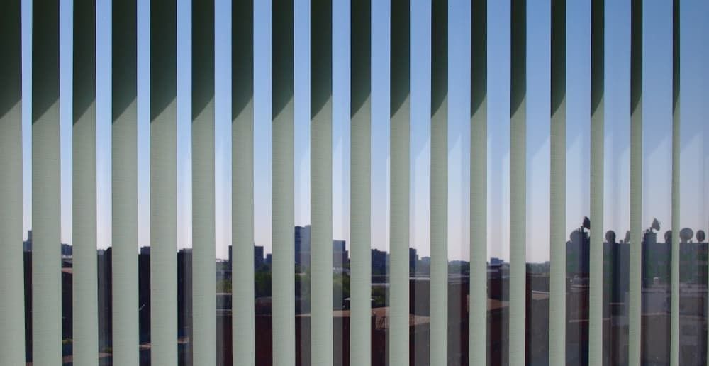 A View of a City Skyline Through Vertical Blinds — Budget Screens & Awnings in South Lismore, NSW