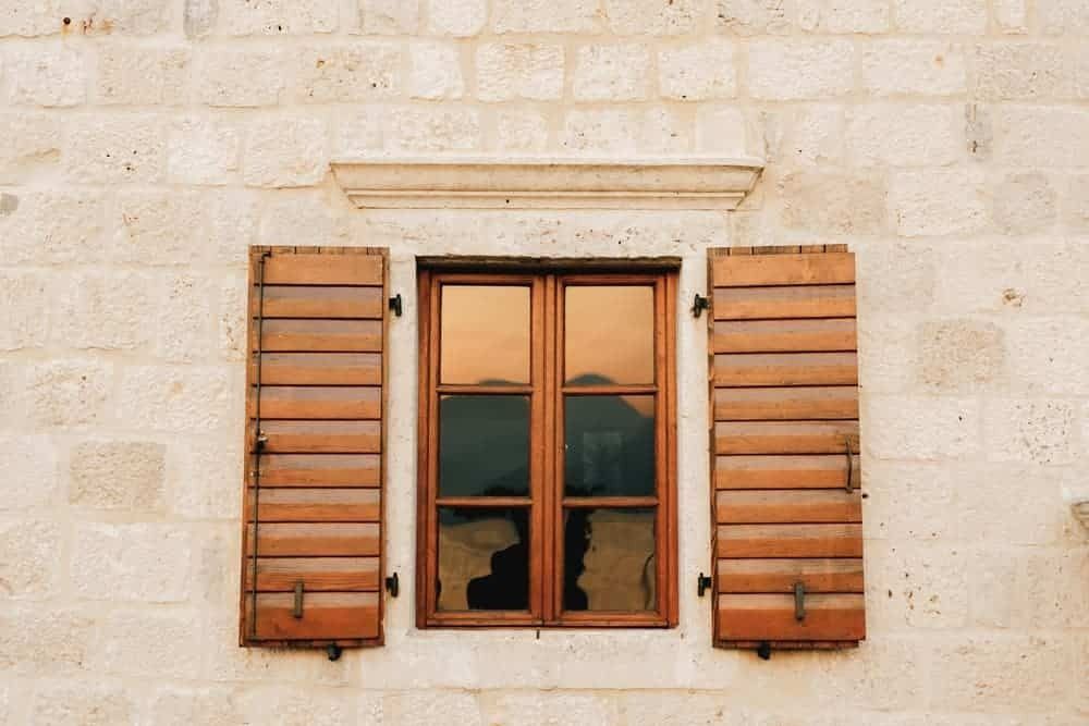 A Window With Wooden Shutters on a Brick Wall — Budget Screens & Awnings in South Lismore, NSW