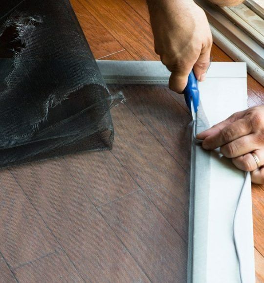 A Person is Cutting a Screen With a Pair of Scissors — Budget Screens & Awnings in South Lismore, NSW