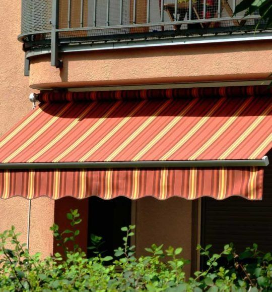 A Red and Yellow Striped Awning on a Balcony — Budget Screens & Awnings in South Lismore, NSW