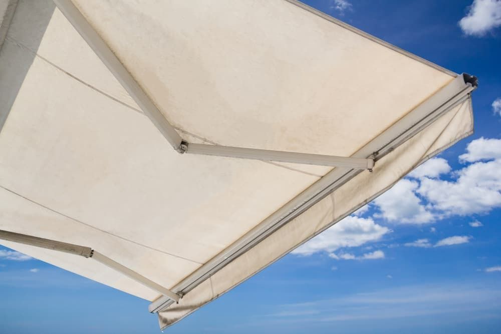 A White Awning is Against a Blue Sky With Clouds — Budget Screens & Awnings in South Lismore, NSW