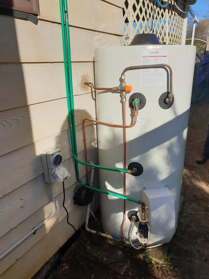 A Water Heater Is Attached To The Side Of A House — Shannon Malone Plumbing In Gerringong, NSW