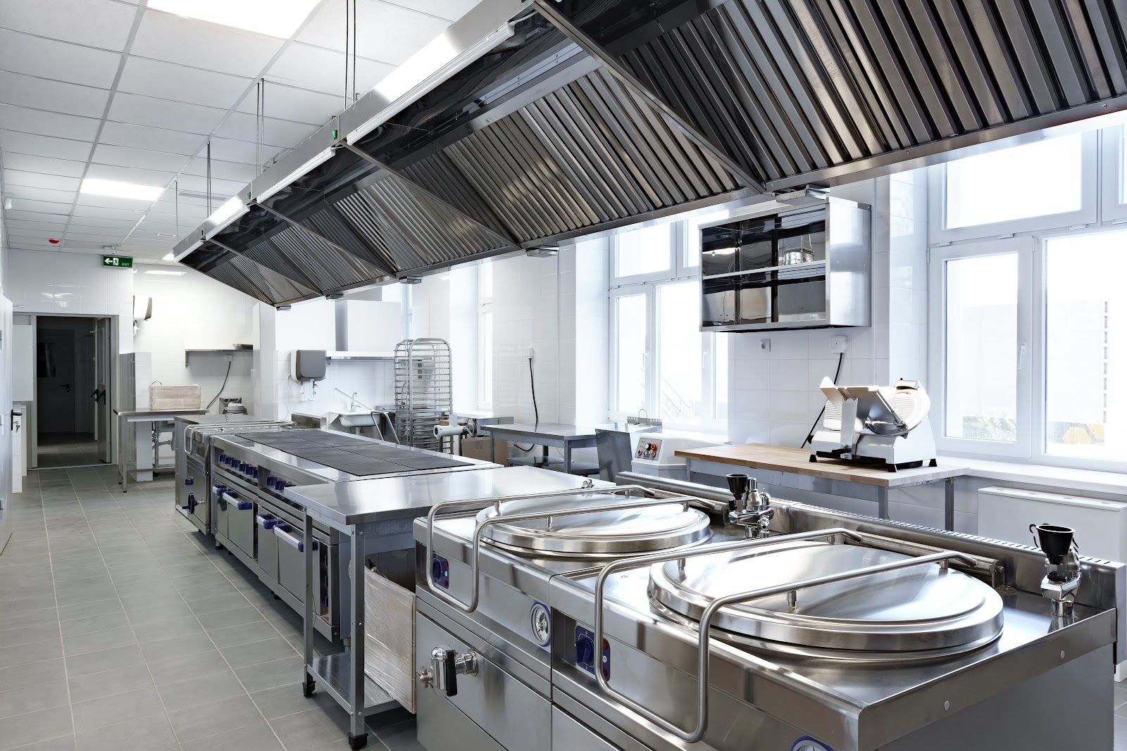 Commercial kitchen with stainless steel equipment and exhaust hoods.