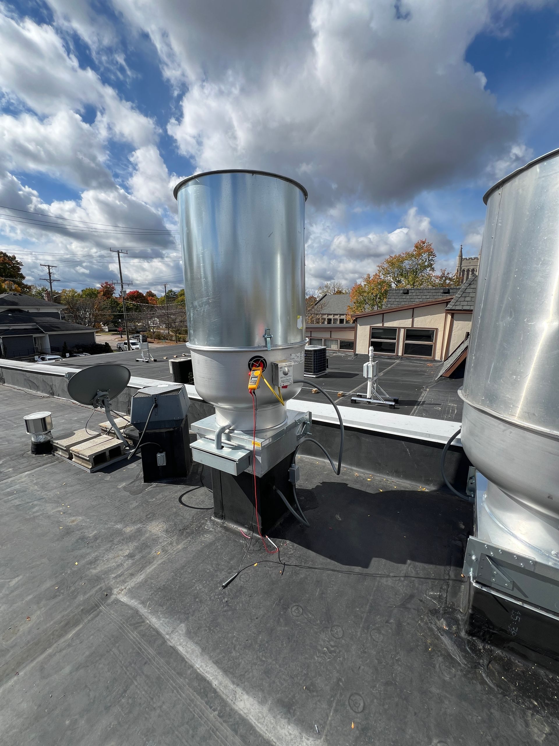 Silver industrial equipment on a rooftop against a cloudy blue sky.