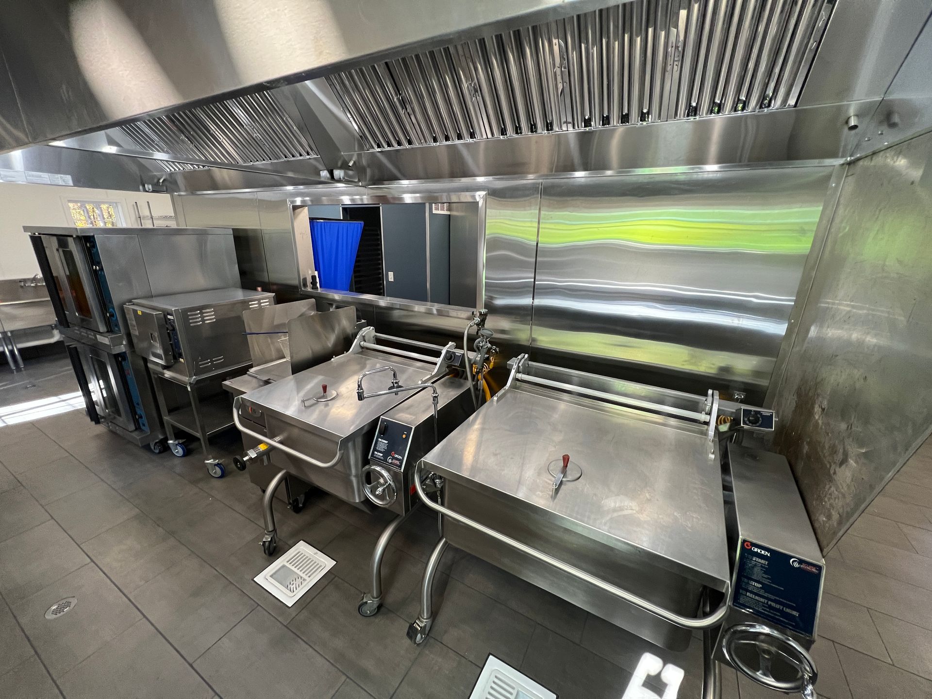 Commercial kitchen with stainless steel equipment and vent hood.