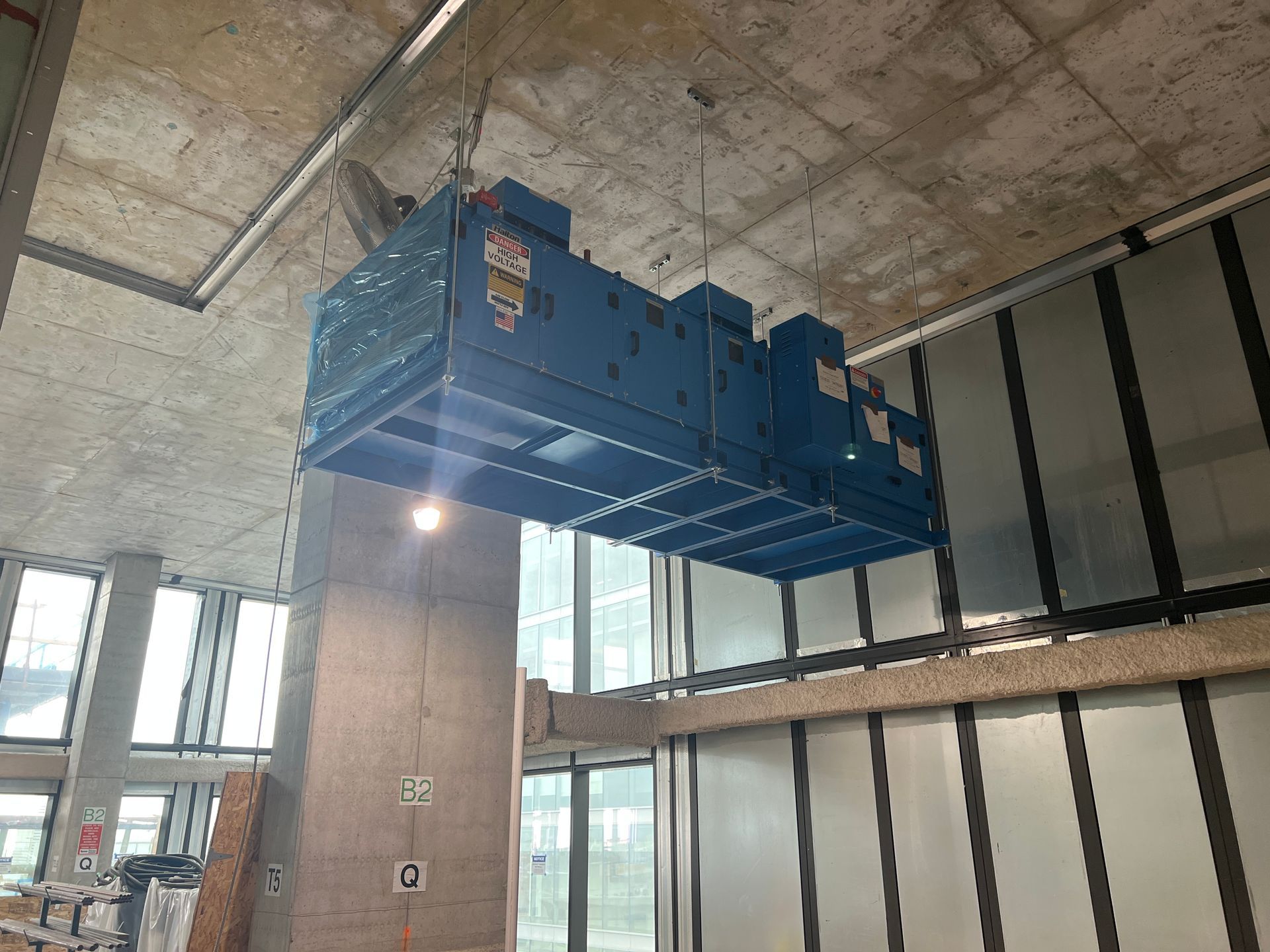 Blue HVAC unit suspended from ceiling in a building.