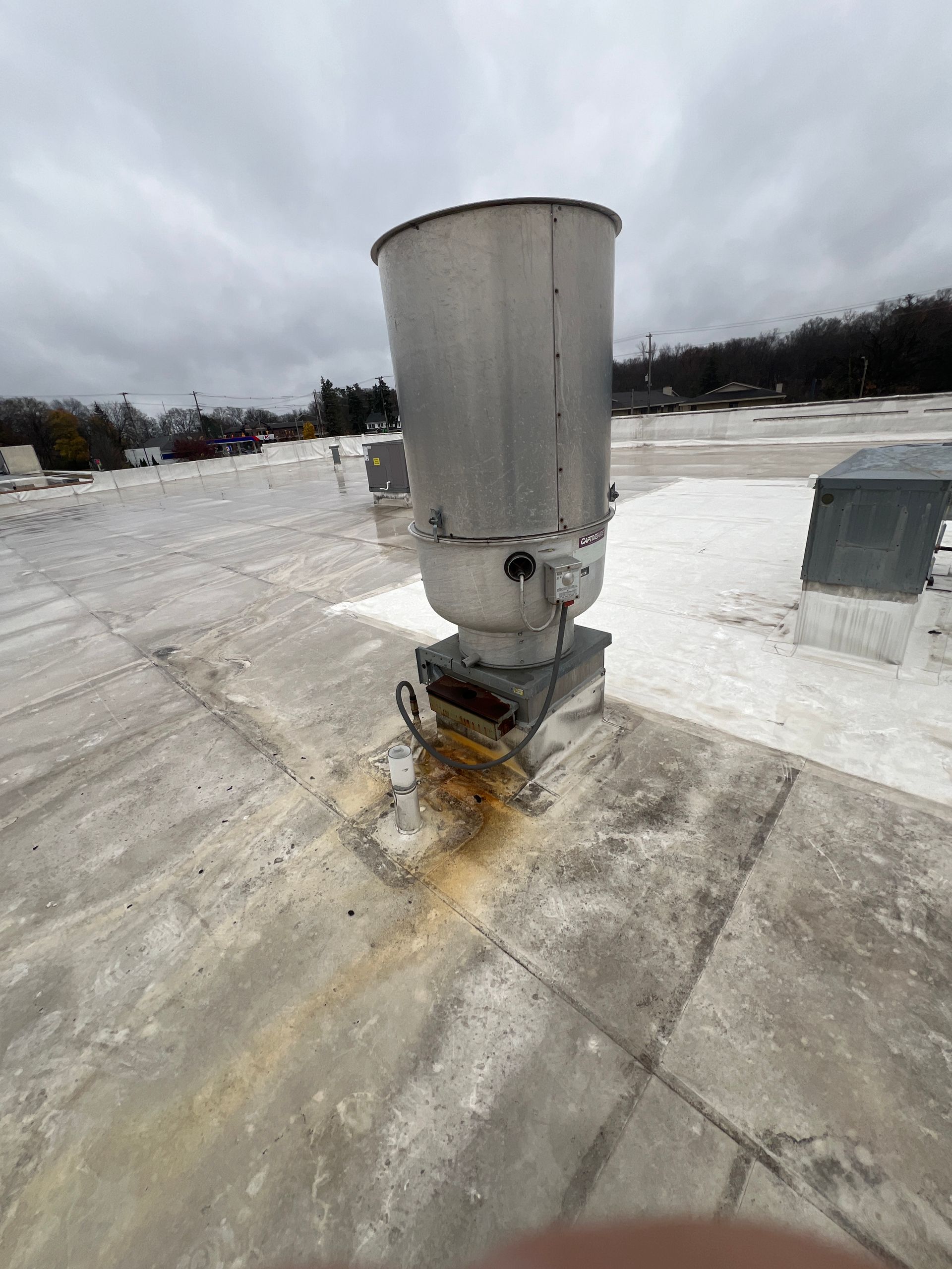 Large metal exhaust vent on a flat roof, possibly leaking. Cloudy sky overhead.