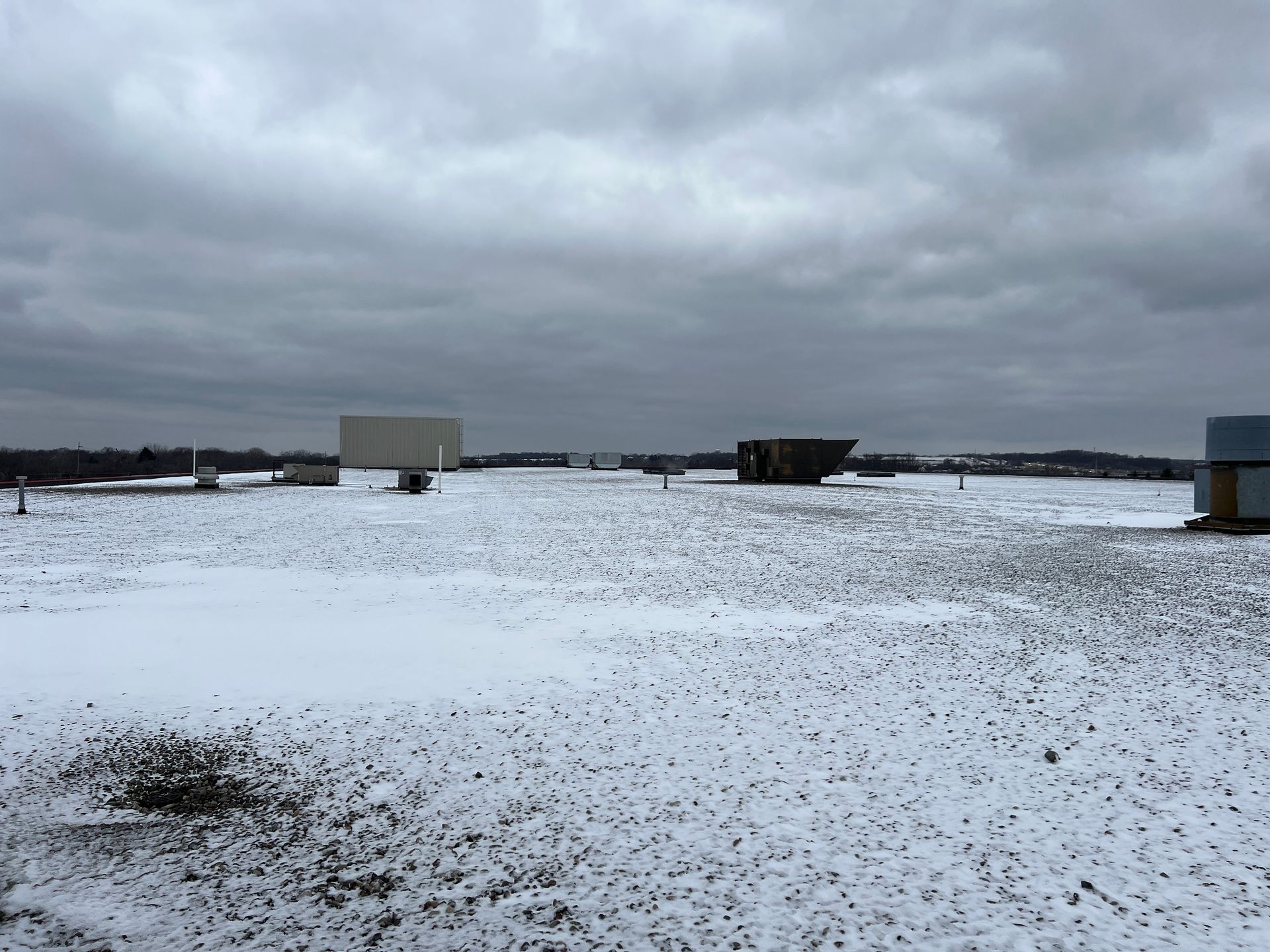 A snow-covered drive-in movie theater on a cloudy day, with multiple screens visible.