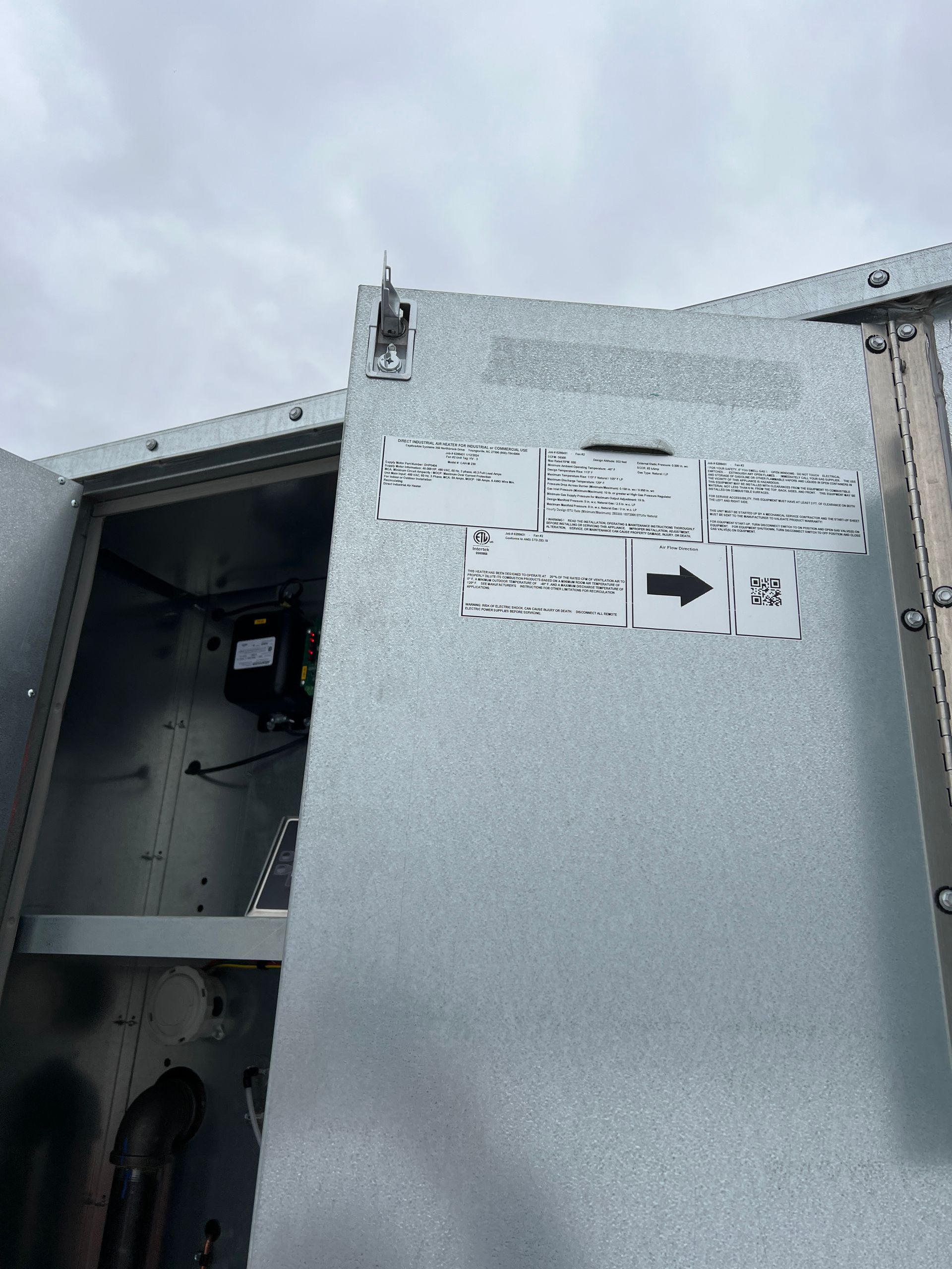 Open metal panel on an HVAC unit with labels and an arrow pointing to the right.