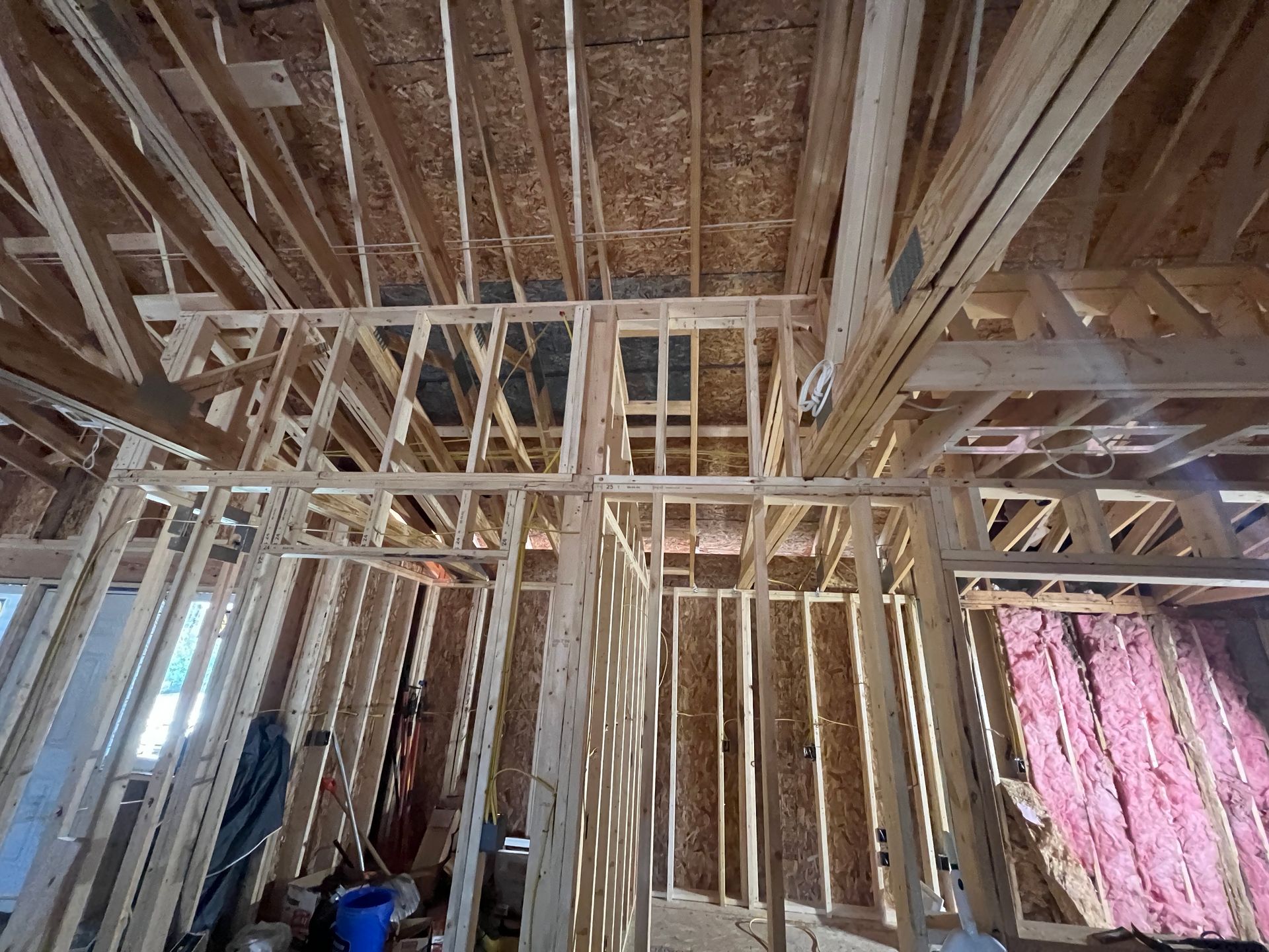 Wooden house framing with exposed beams and insulation visible.
