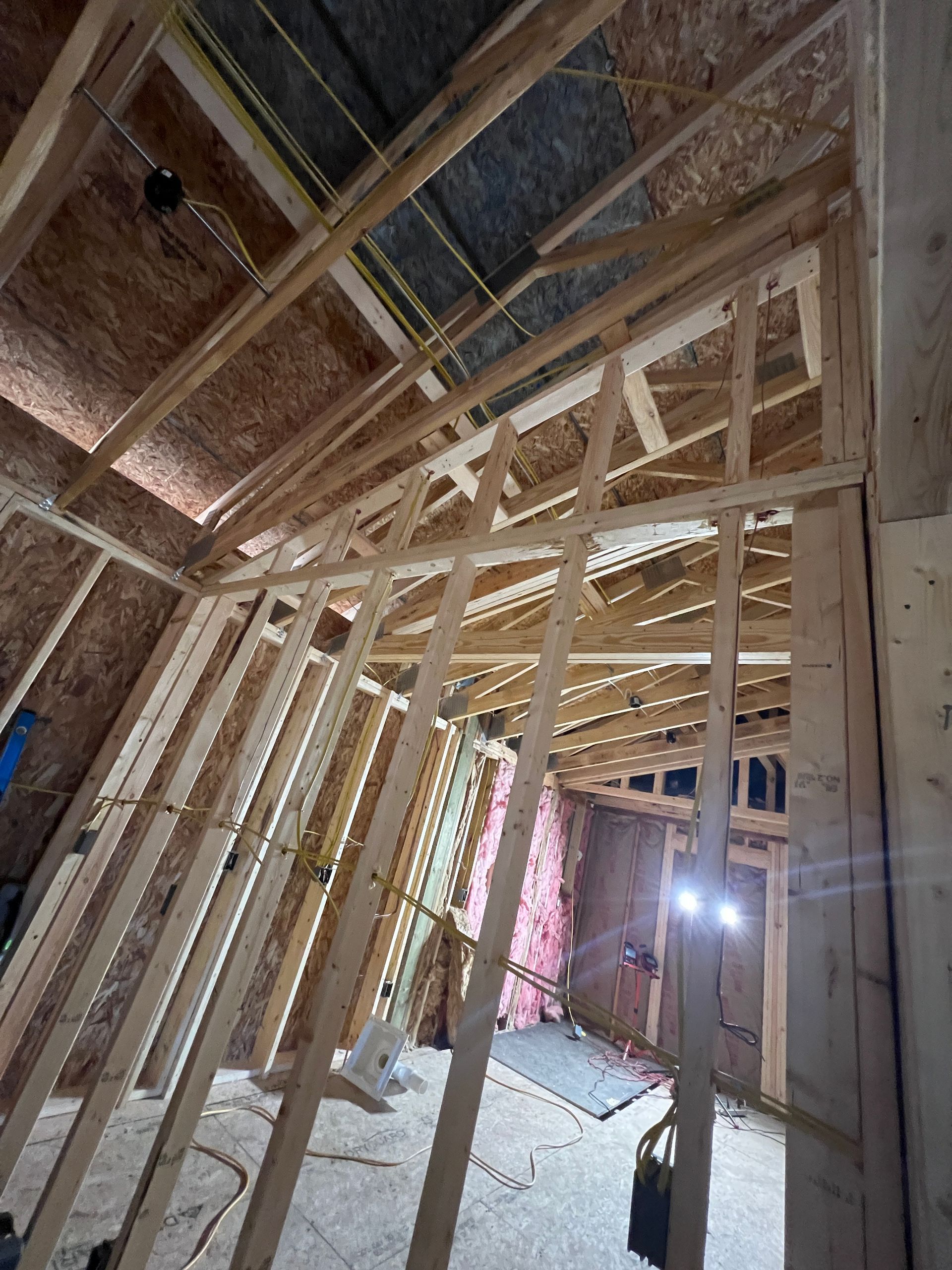 Interior framing of a room under construction with wood studs and exposed rafters.