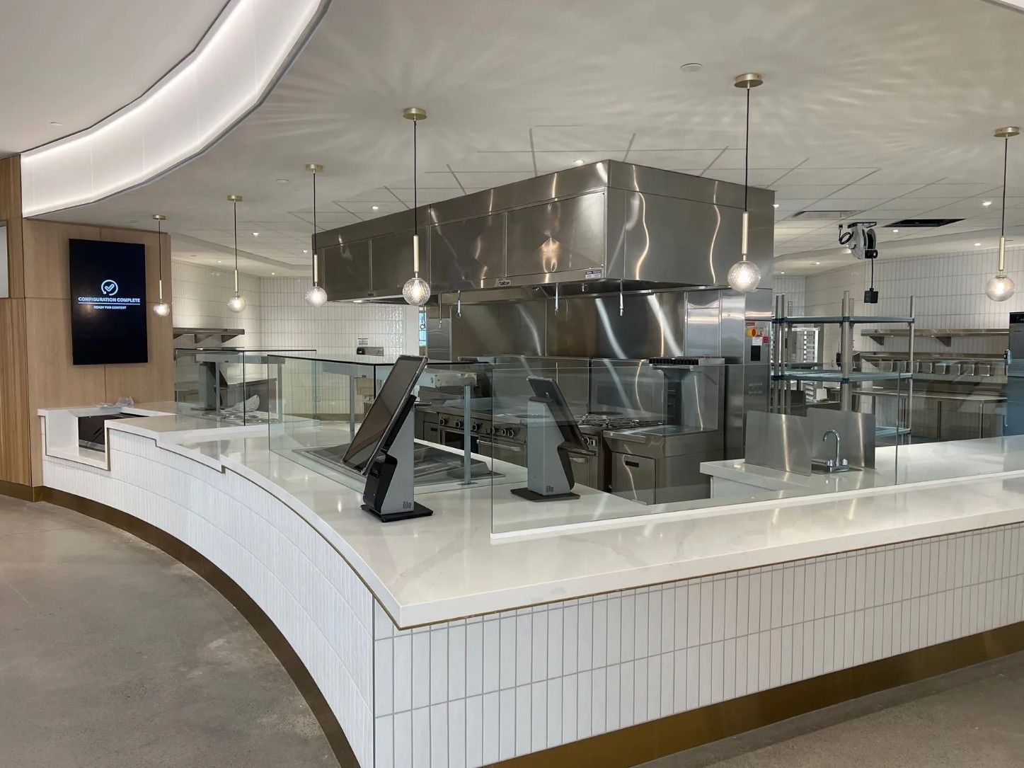Modern open kitchen with stainless steel appliances, white tile, and a curved counter.