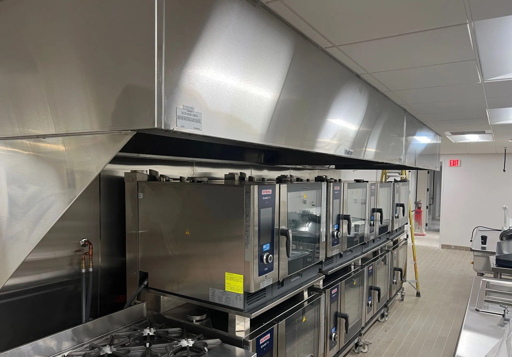 Stainless steel kitchen hood above commercial ovens.