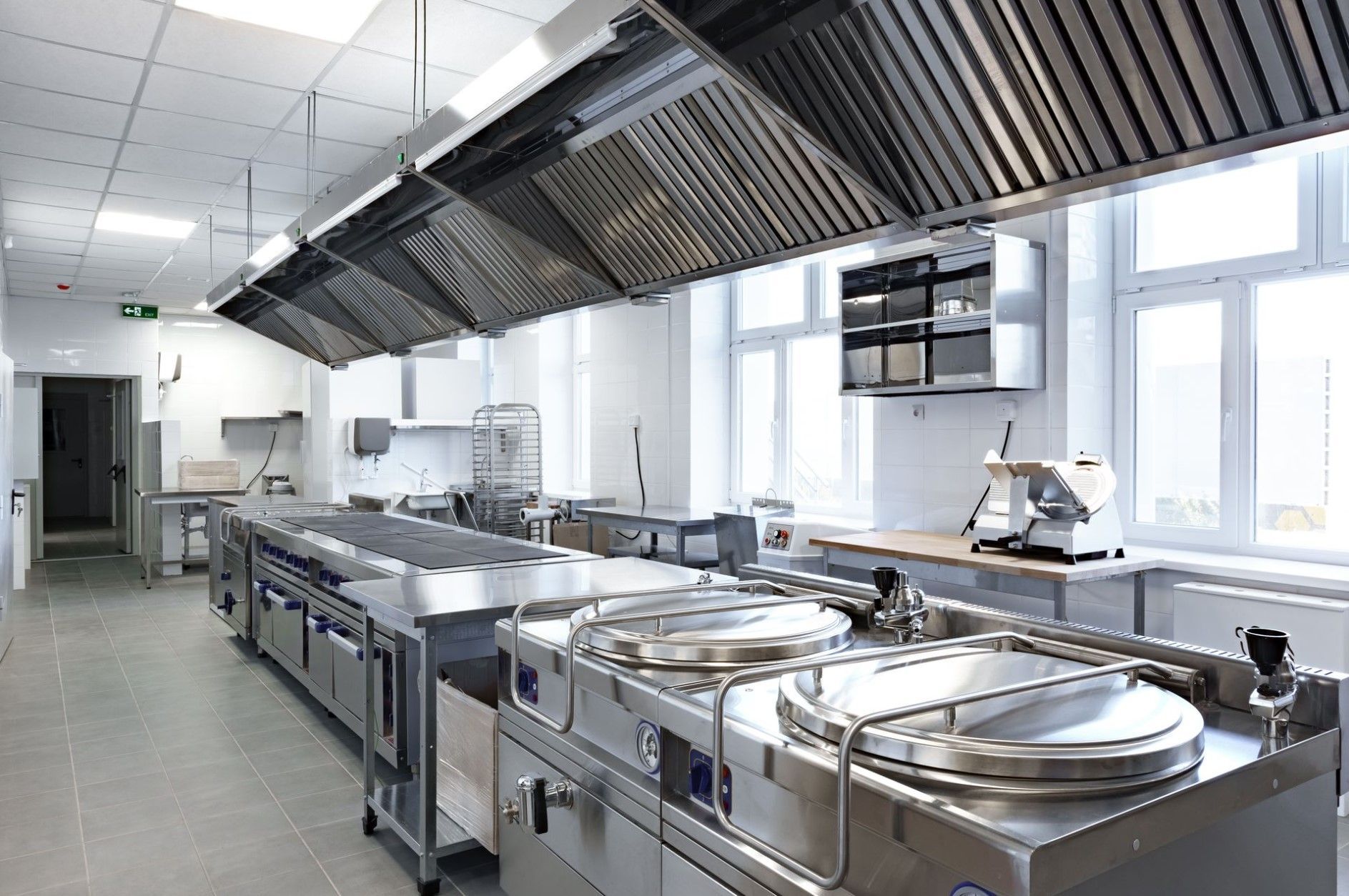 Commercial kitchen with stainless steel equipment and range hoods.