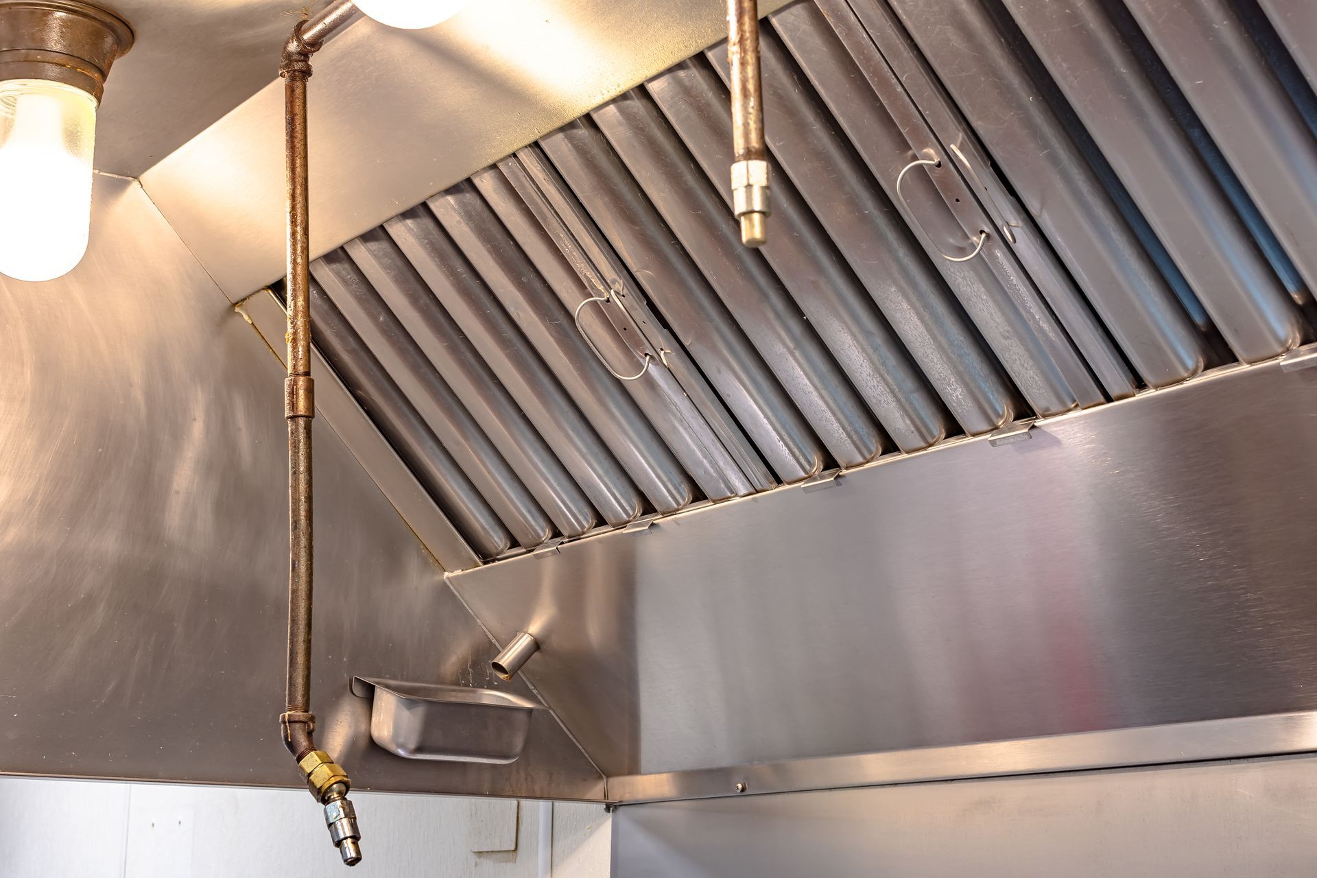 Stainless steel commercial kitchen exhaust hood with light and fire suppression system.