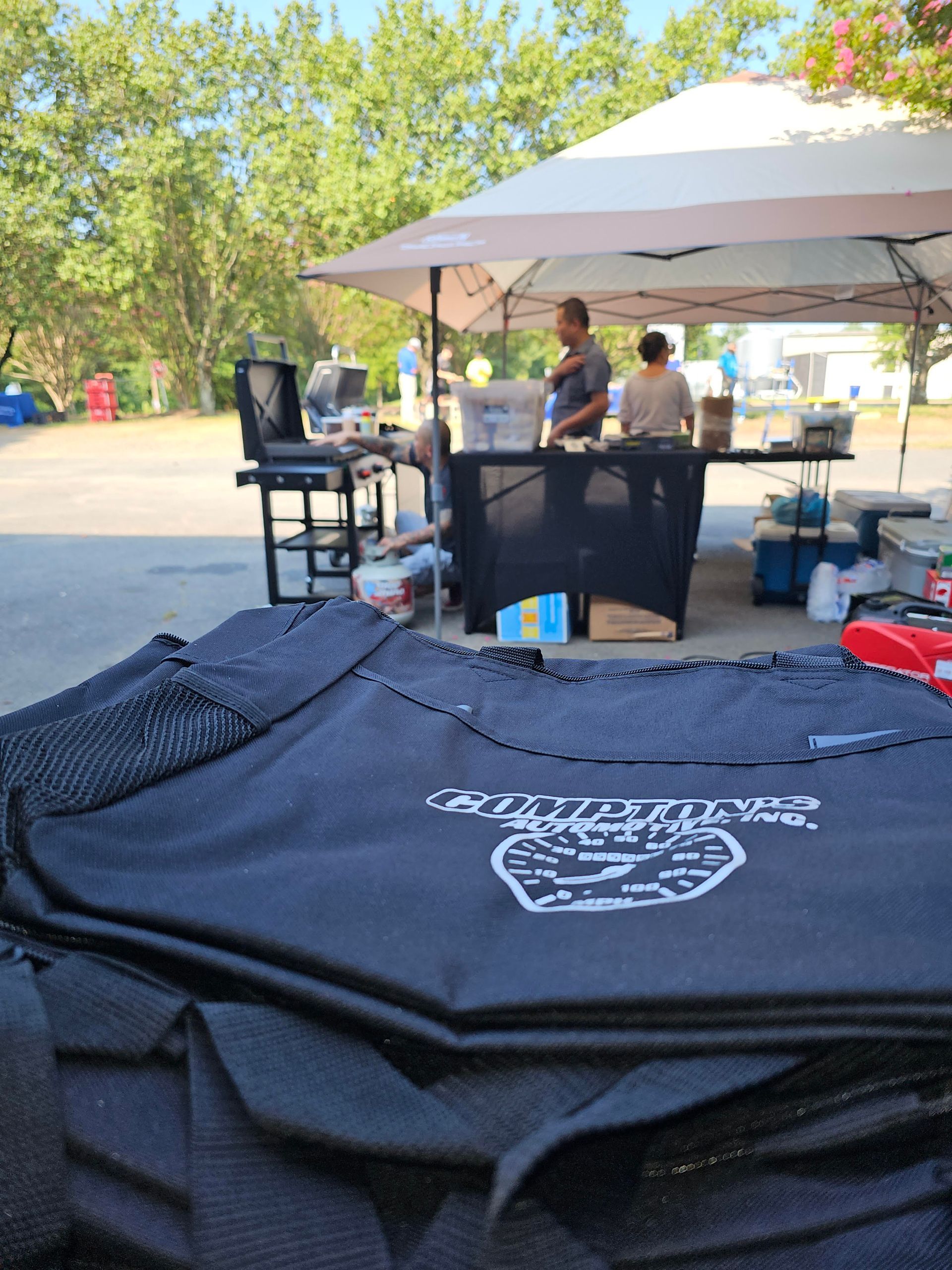 People preparing food under a canopy; black bags in foreground.