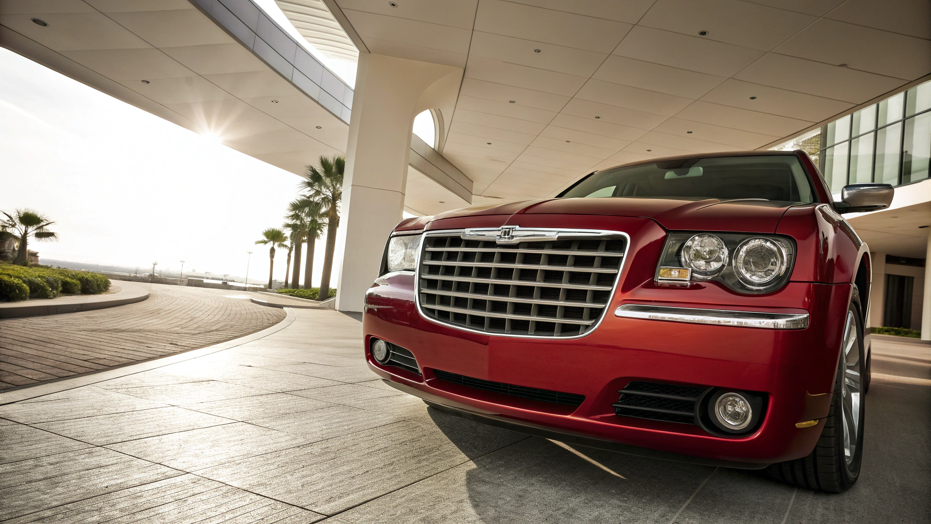 A sleek red luxury car is parked under a modern building's canopy.