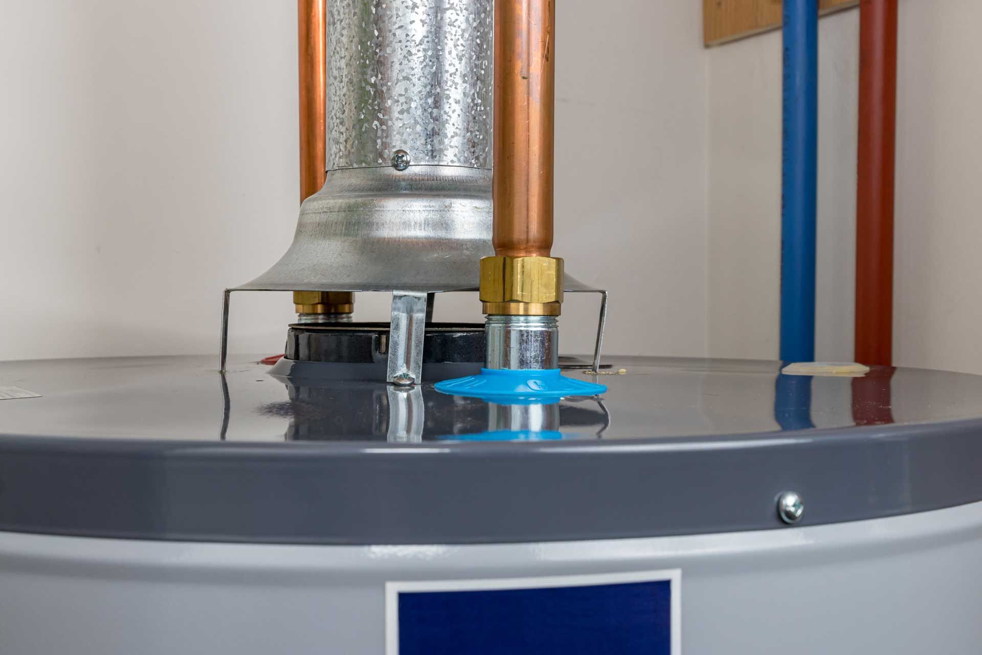 Water heater with copper pipes, vent, and blue plastic.