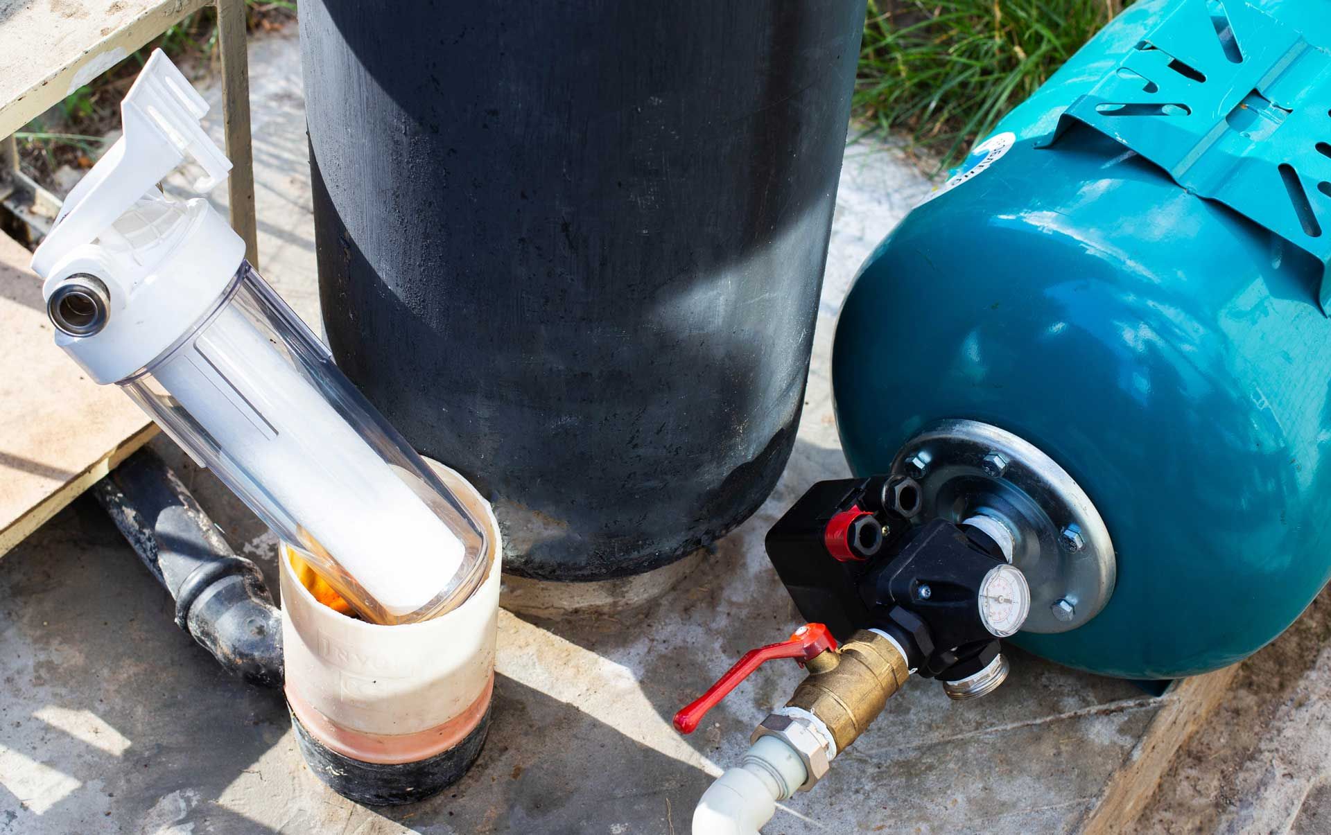 Water filtration system setup with a blue tank, white filter housing, and black control valve.