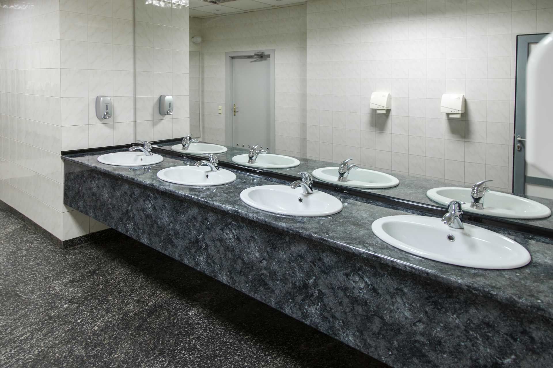 Public restroom with multiple sinks, mirrors, soap dispensers, and paper towel dispensers.