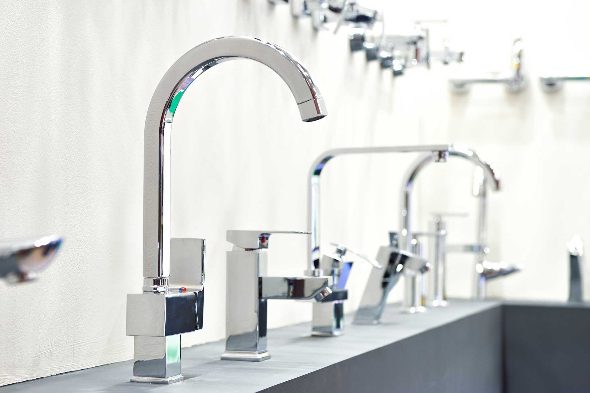 Row of shiny chrome faucets displayed in a showroom.