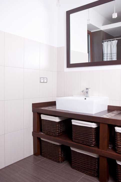 Bathroom with white tiled walls, dark brown vanity with woven storage baskets, and a large mirror.
