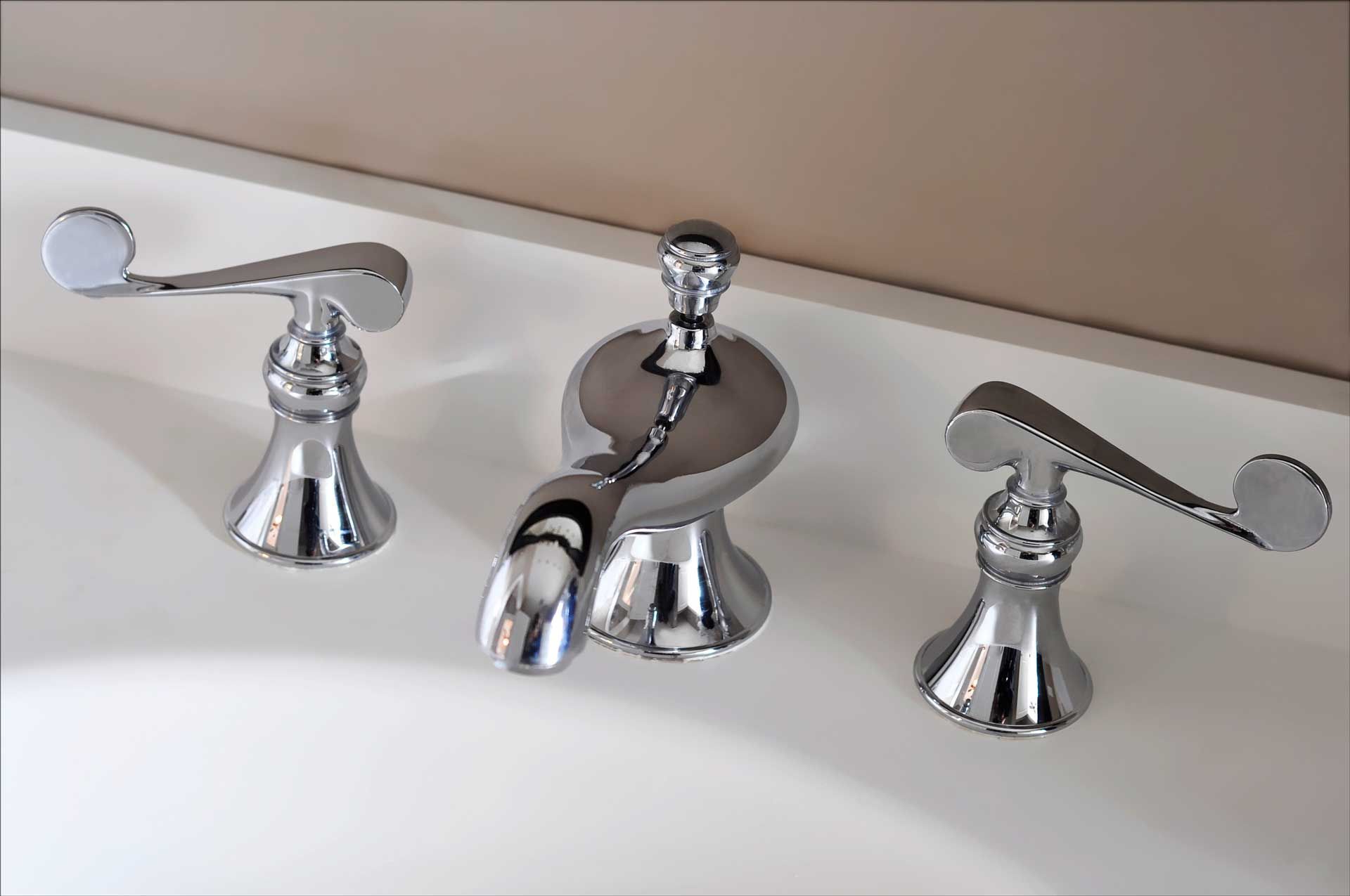 Close-up of a three-piece chrome bathroom faucet set on a white surface.