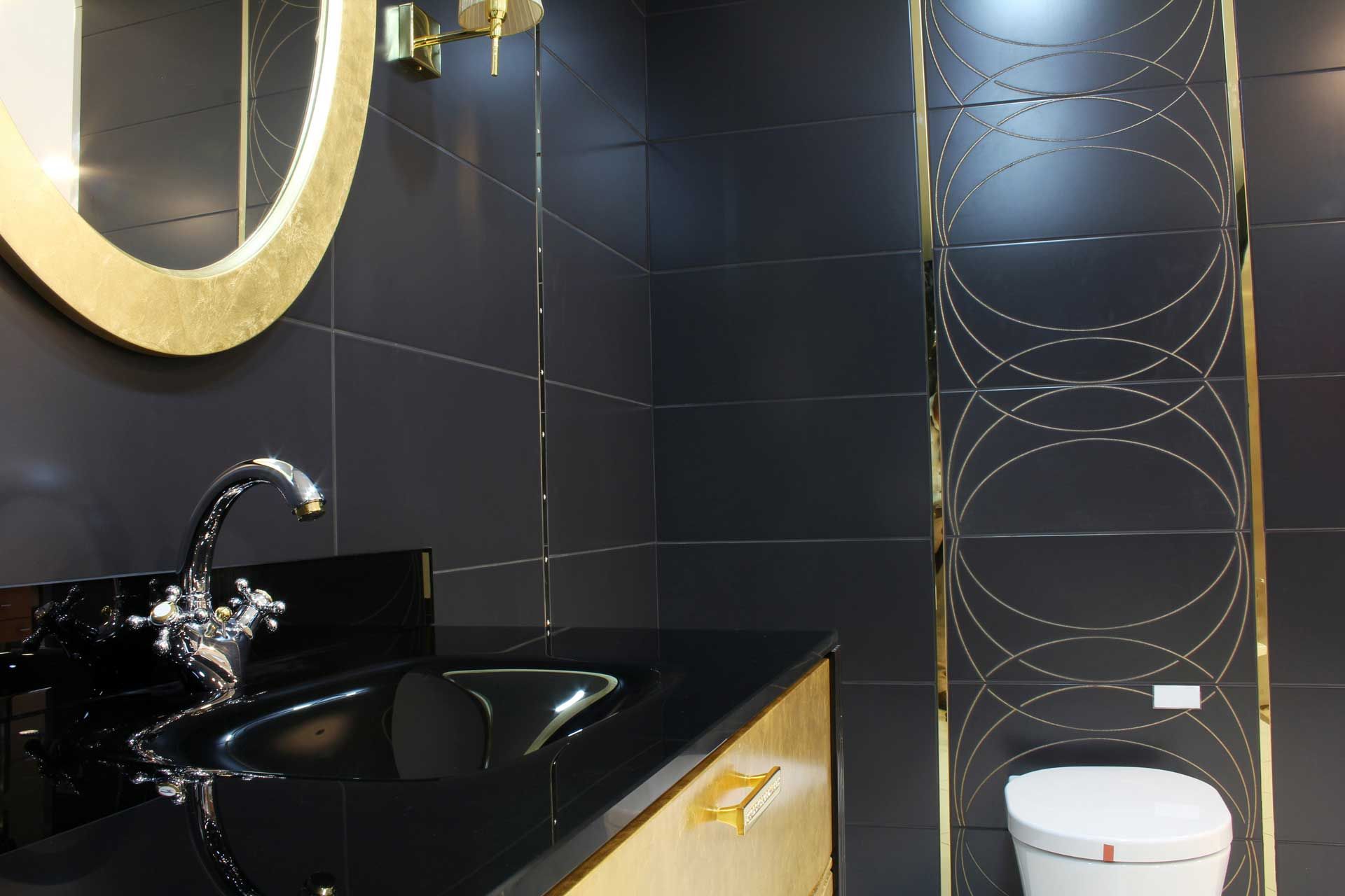 Black and gold bathroom with sink, mirror, and toilet.