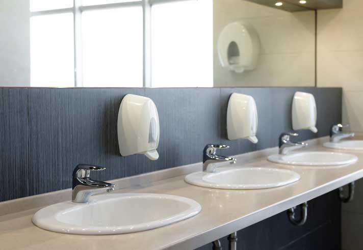 A row of sinks and soap dispensers in a public restroom.