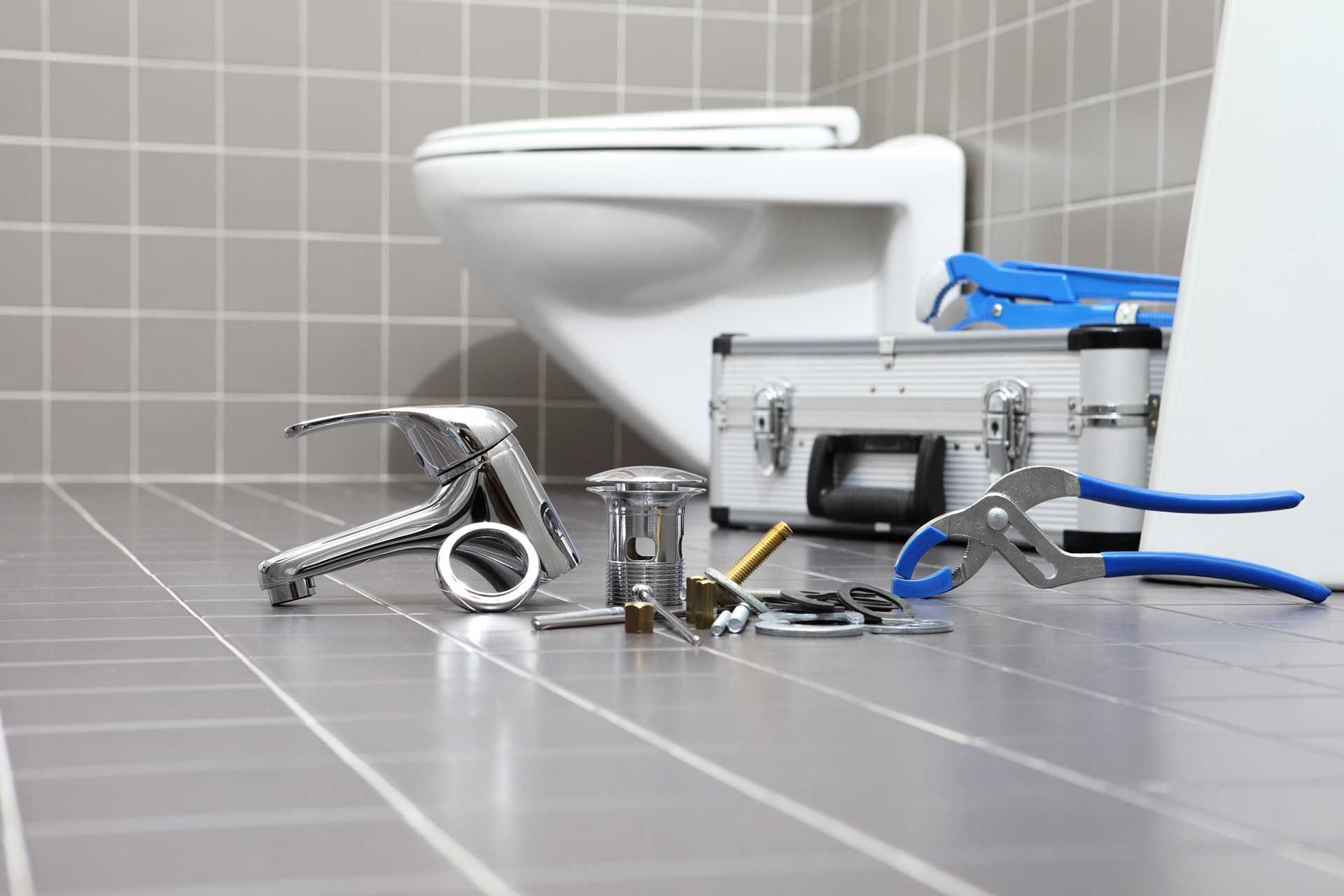 Toilet and plumbing tools on bathroom floor.