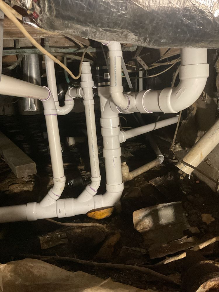 White PVC pipes in a crawl space, connecting to a drain system. White PVC pipes in a crawl space, connecting to a drain system.