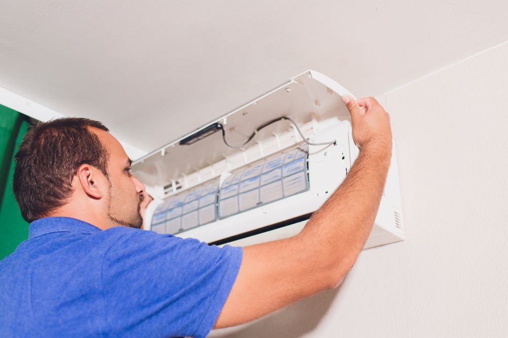 Man Removing the Cover of A Mounted Air Conditioner — Projected Contracting Electrical Services In Mossman, QLD
